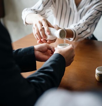 person pouring a drink on cup