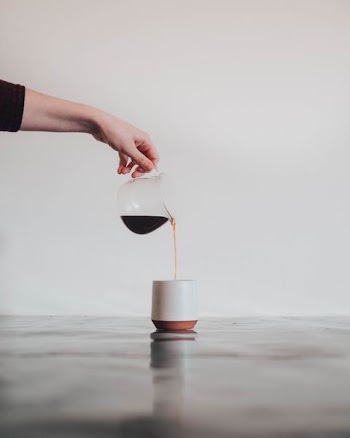 person pouring coffee in white mug