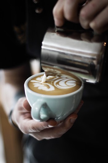 Person Pouring Cream in Espresso