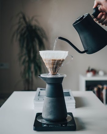 person pouring hot water on pour-over coffee maker
