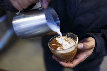 Person Pouring Milk on Coffee