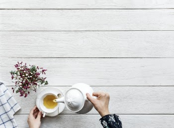 Person Pouring Tea on a Cup