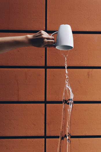 Person Pouring Water from Cup