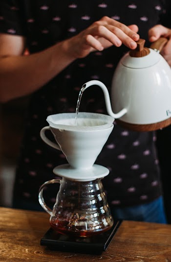 Person Pouring Water in Clear Glass Teapot