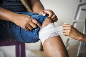 Person Putting Bandages on Another Person's Knee