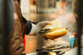 Person Putting Grilled Food in Sliced Bread