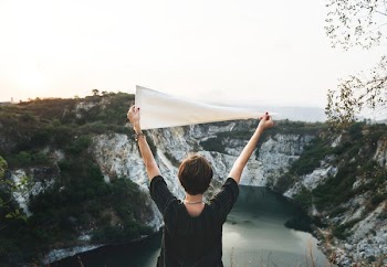 person raising white pennant flag in front of lake