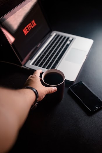 Person Reaching for Mug With Coffee Near Macbook Pro and Space Gray Iphone 6