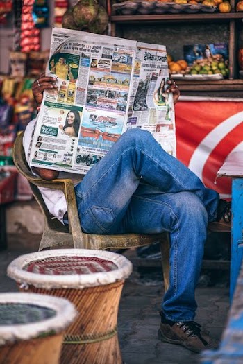 person reading newspaper sitting on armchair