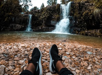 Person Resting on Ground Facing Waterfalls