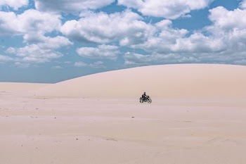 person rides on motorcycle under white sky