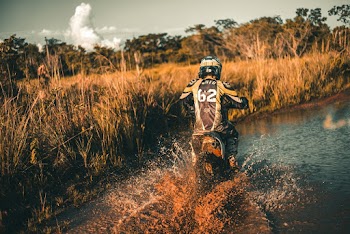 Person Riding Dirt Bike in Middle of River