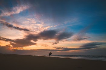 person riding horse at seashore near body of water under cloudy sky
