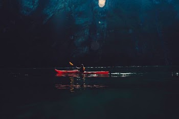 person riding on red kayak while paddling on body of water