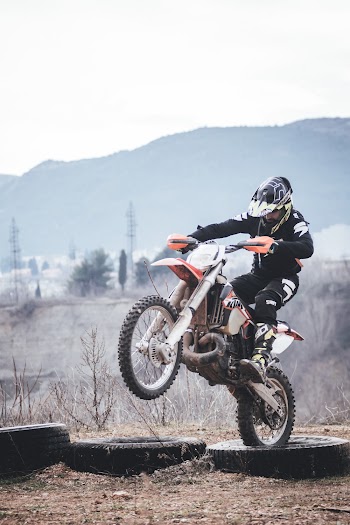 Person Riding Orange and White Dirt Bike