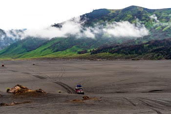 Person Riding Red Car on Vast Land Near Mountains