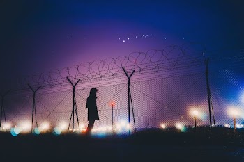 person's silhouette standing near chain link fence