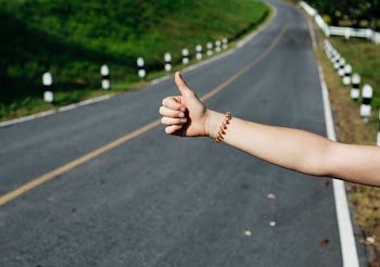 person's thumbs up gesture on road