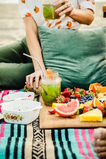 person siting on mat in front of fresh fruits and cheese slices