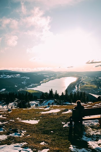 Person Sits on Bench on Top of the Mountainn