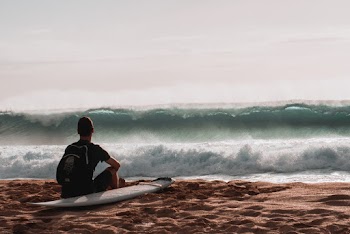 Person Sitting At The Beach With Surfboard