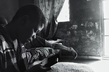 Person Sitting Beside Bed In Grayscale Photography
