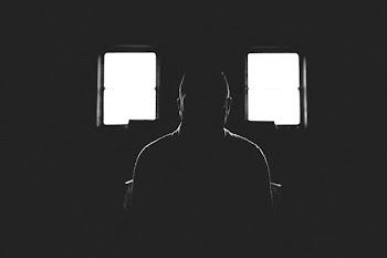Person Sitting in Dark Room With 2 Window
