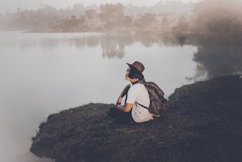 Person Sitting Near Calm Body Of Water