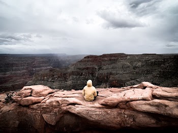 Person Sitting On Brown Rock Formation