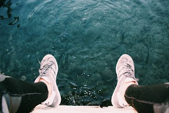 Person Sitting on Cliff Near Water