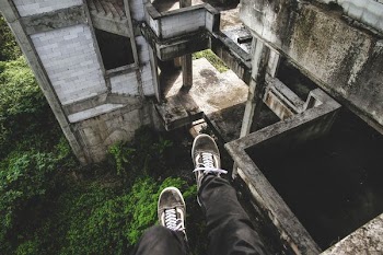 person sitting on gray abandoned building