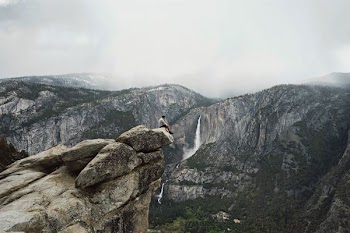 person sitting on mountain cliff