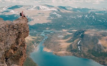 person sitting on mountain cliff