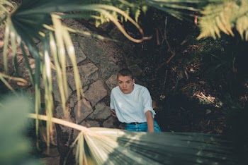 Person Sitting on Pathway Near Plants