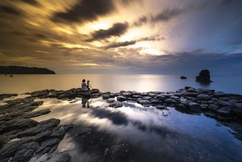 Person Sitting On Rock In Front Of Body Of Water