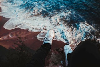 person sitting on rock near seashore