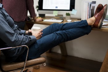 Person Sitting on Rolling Armchair and His Feet on the Desk