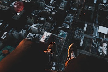 Person Sitting on Roof Top Viewing City With High-rise Buildings