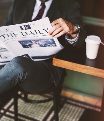 Person Sitting On Stool While Reading The Daily Newspaper