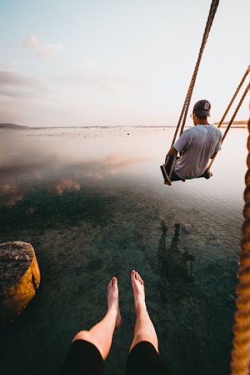person sitting on swing on top of body of water