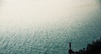 person stand on rock near body of water during daytime