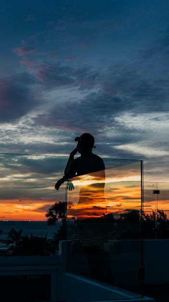 Person Standing Beside Glass Wall during Golden Hour