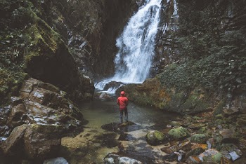 Person Standing Beside Waterfalls