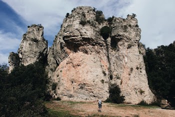 Person Standing Near Brown and Grey Rock Formation