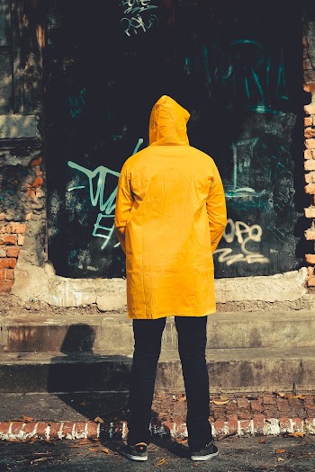 Person Standing Near Brown Structure in Yellow raincoat