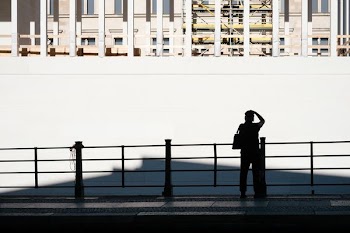 person standing near fence watching white wall