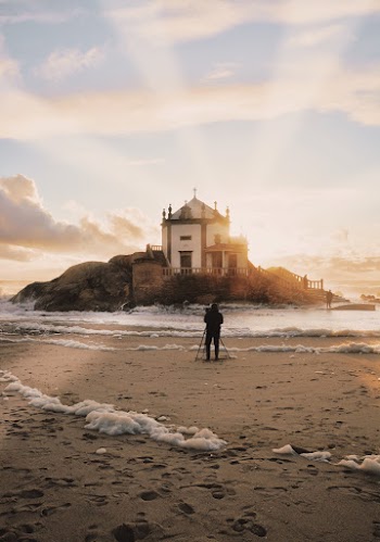 Person Standing Near Sea Shore Overlooking Island during Golden Hour