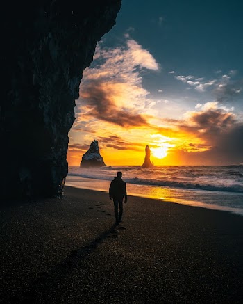 Person Standing Near Seashore Viewing Mountain Island Under Yellow and Blue Sky