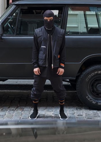 person standing near vehicle wearing balaklava and black jacket