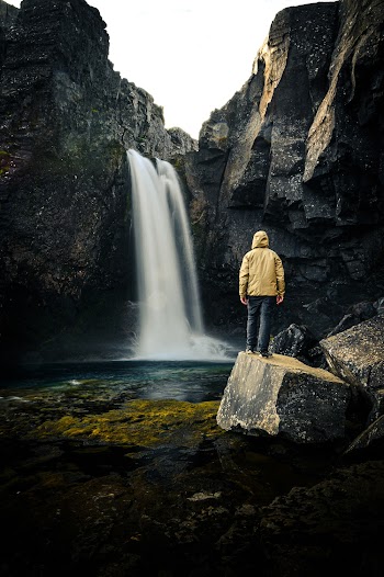 Person Standing Near Waterfalls